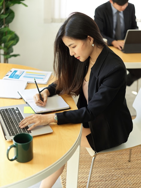 Foto recortada de uma mulher de negócios se concentrando em seu trabalho com um laptop e um papel de carta na sala do escritório