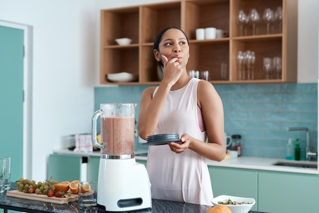 Foto recortada deliciosa de uma jovem atraente fazendo smoothies em sua cozinha em casa