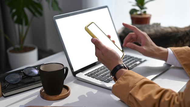 Foto recortada do empresário usando pone móvel enquanto trabalhava com computador portátil na mesa de escritório