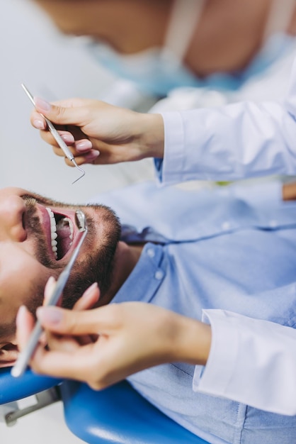 Foto foto recortada do médico verificando os dentes do paciente com espelho na clínica odontológica moderna