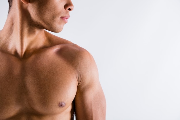 Foto recortada de guapo deportista musculoso chico de piel oscura demostrando su cuerpo perfecto