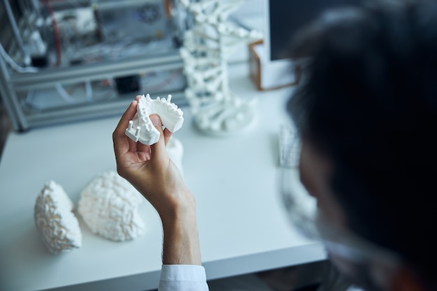 Foto foto recortada de un hombre caucásico sosteniendo el modelo de dientes impreso en 3d en su mano