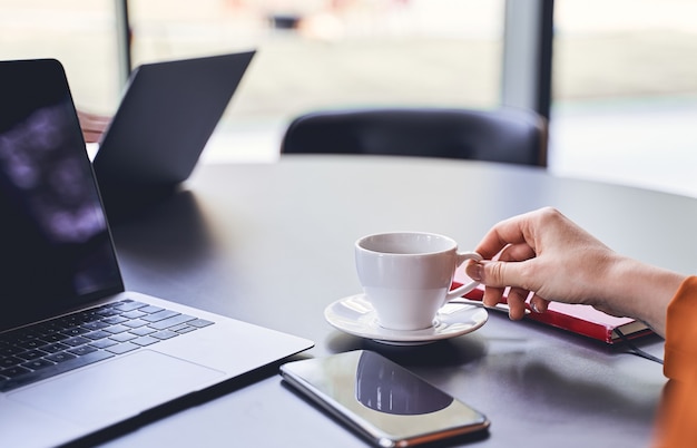 Foto recortada de una joven empresaria caucásica con un portátil sentado en un escritorio de oficina