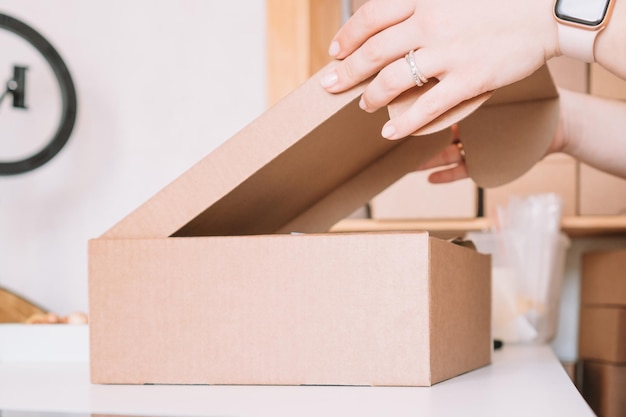 Foto recortada de las manos de la mujer empacando la preparación del paquete para el paquete de entrega a los clientes Pedido en línea de pequeñas empresas