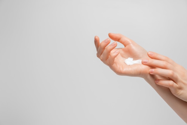 Foto recortada de mujer aplicando crema orgánica en la mano. Mujer joven aplicando crema de manos.