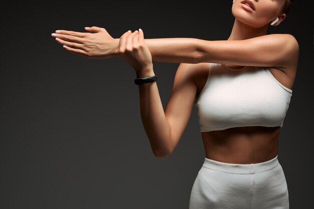 Foto recortada de una mujer fitness estirando las manos aislada sobre fondo gris Copiar espacio