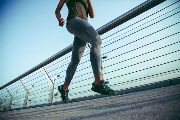 Foto recortada de una mujer en ropa deportiva corriendo al aire libre durante el día