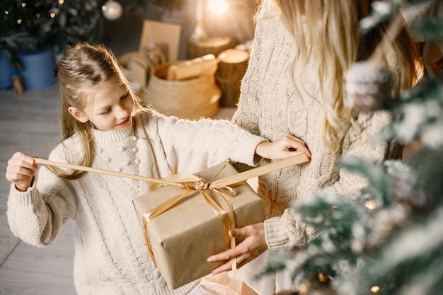 Foto recortada de una niña parada cerca del árbol de navidad en casa con su madre