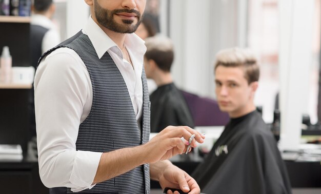 Foto recortada de peluquero trabajando en barbería usando tijeras afiladas