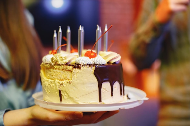 Foto recortada de un plato con pastel de cumpleaños en manos de mujer