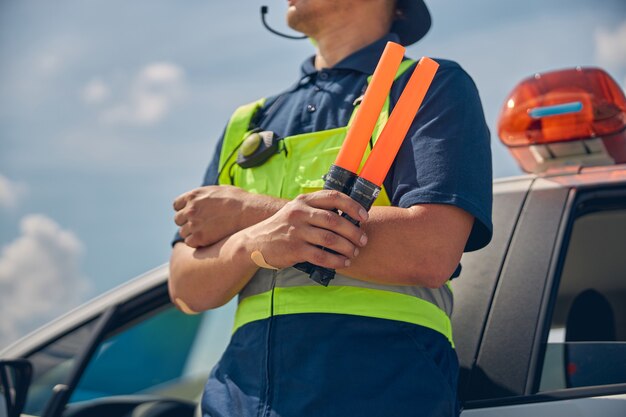 Foto recortada de un trabajador de sexo masculino con el mono de seguridad apoyando la espalda contra el automóvil