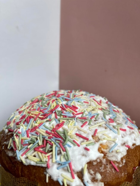 Foto foto recortada vertical de um bolo de páscoa paska coberto com glacê branco e granulado colorido