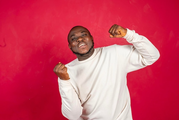 foto de regocijo alegre alegre feliz hombre negro bailando de alegría mientras está aislado con fondo rojo