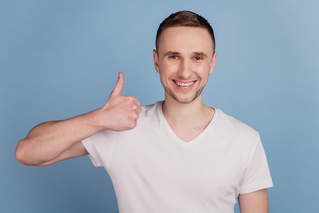 Foto retrato de homem feliz sorriso positivo mostrando sinal de polegar como isolado no fundo de cor azul
