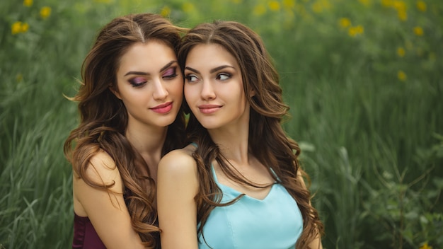 Foto de retrato de moda de dos mujeres contra el prado de hierba verde en la naturaleza