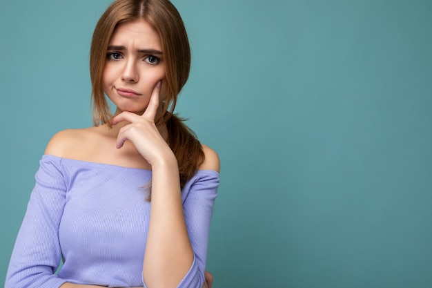 Foto retrato de moody pensativo joven agradable hermosa mujer rubia con emociones sinceras vistiendo top azul de moda