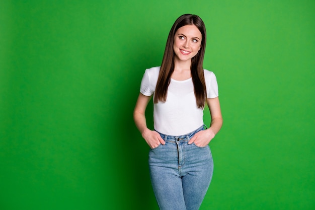 Foto retrato de mujer dulce encantadora vestida con traje casual manos brazos bolsillos mirando el espacio vacío aislado de fondo de color verde