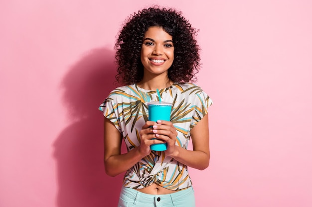 Foto retrato de mujer sosteniendo un vaso de papel en dos manos aislado sobre fondo de color rosa pastel