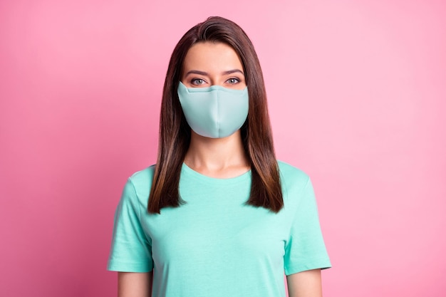 Foto retrato de niña vistiendo mascarilla de tela verde azulado aislada sobre fondo de color rosa pastel