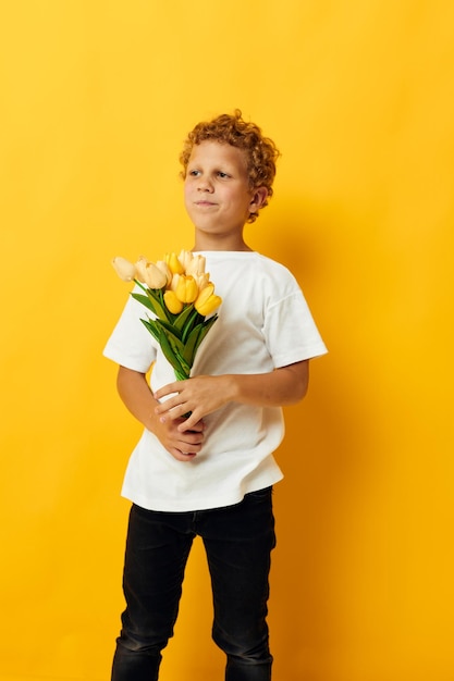 Foto retrato niño rizado con un ramo de flores amarillas fondo aislado inalterado