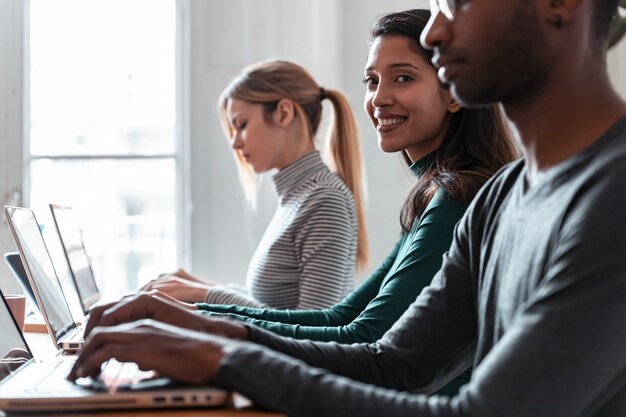 Foto de retrato de vista lateral de una empresaria que trabaja con el portátil entre otros colegas en el lugar de coworking.