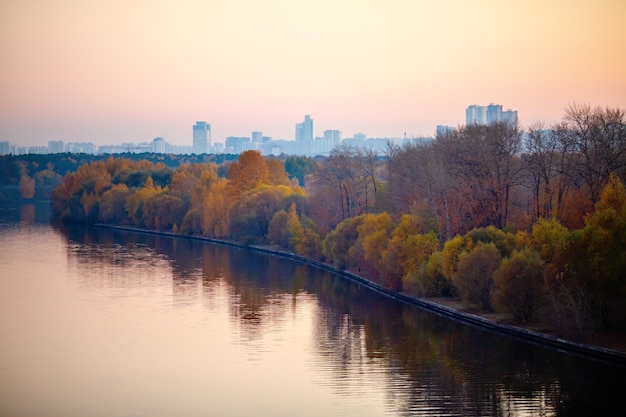 Foto de río, árboles, ciudad al atardecer.