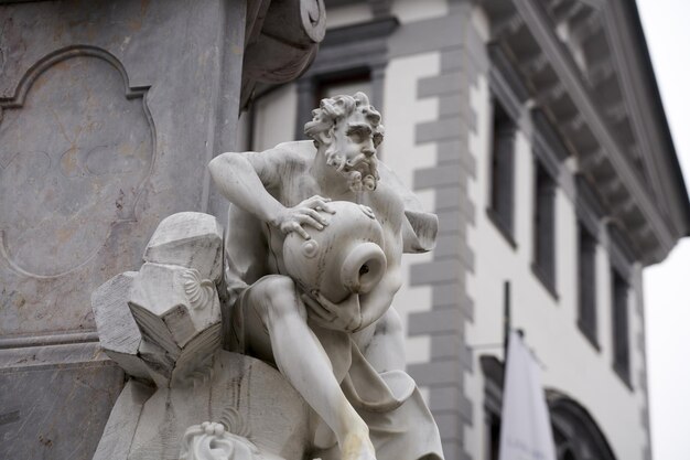 Foto seletiva de uma estátua de um homem segurando uma tigela em frente a um prédio