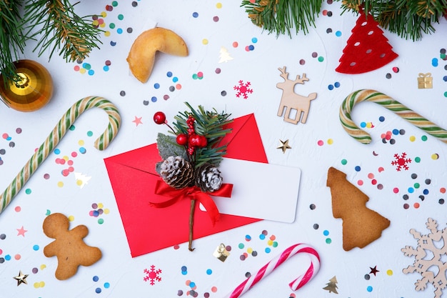 Foto de sobre rojo, galletas, ramas de abeto Adornos navideños en blanco vacío