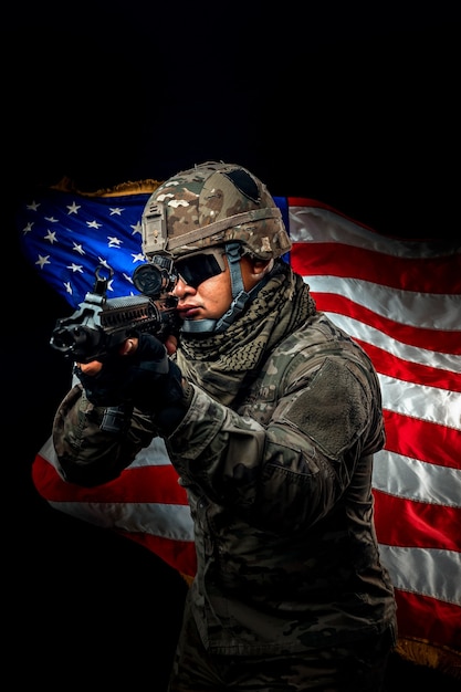 Foto foto de soldado sosteniendo la bandera de estados unidos en segundo plano. soldado de la fuerza especial de los estados unidos o contratistas militares con rifle. imagen de fondo. concepto de soldado, ejército, guerra, armas y tecnología.