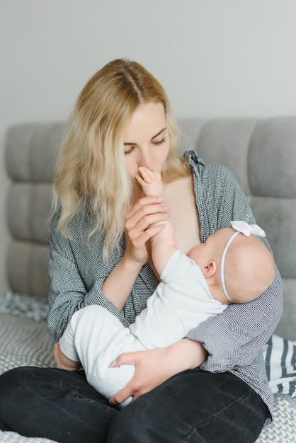 Foto suave joven madre amamantando a su bebé en casa en la habitación blanca