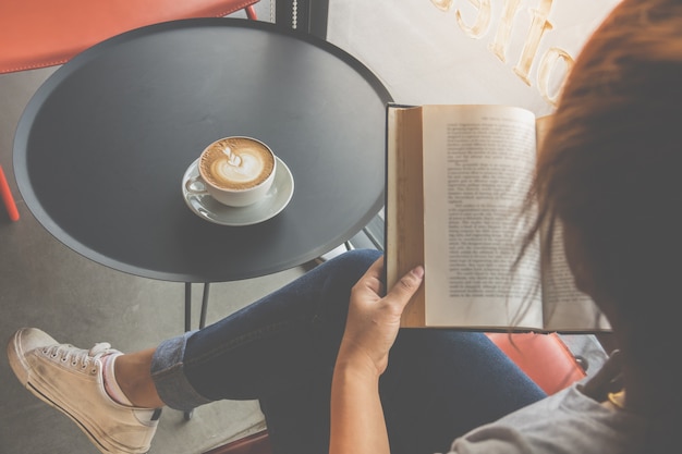 Foto suave de niña leyendo un libro y tomando café