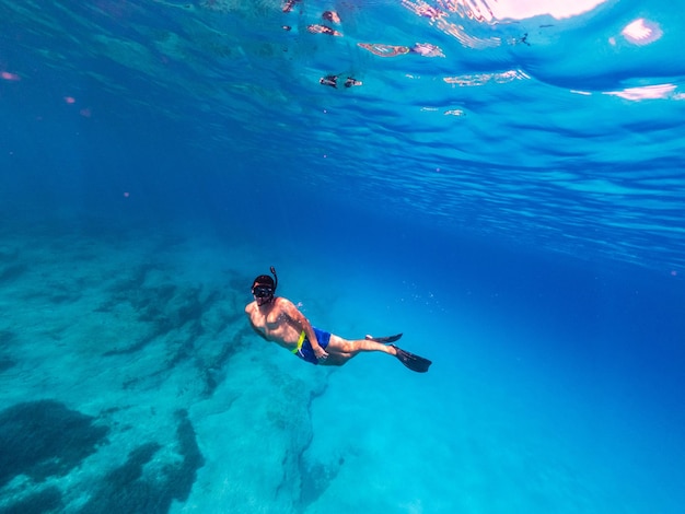 Foto subaquática de homem mergulho livre em mar claro