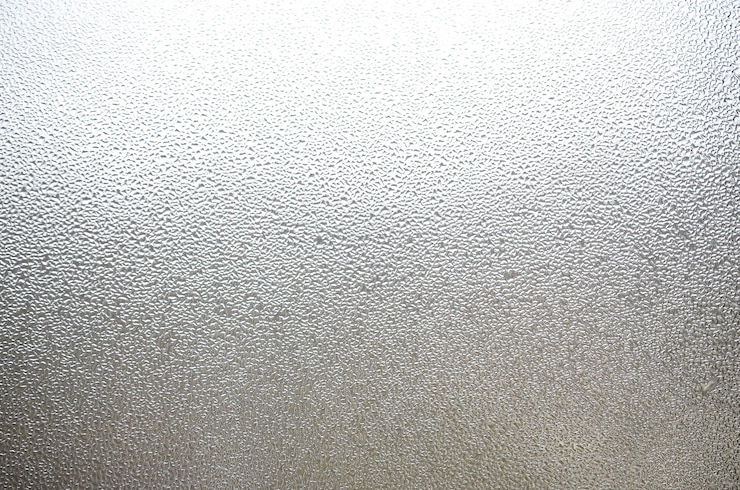 Foto una foto de la superficie de vidrio de la ventana, cubierta con una multitud de gotas de varios tamaños. textura de fondo de una densa capa de condensado sobre vidrio
