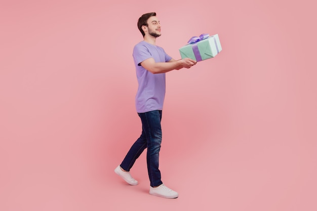 Foto de tamaño completo de chico joven feliz sonrisa positiva mantenga caja de regalo ir a caminar aislado sobre fondo de color rosa