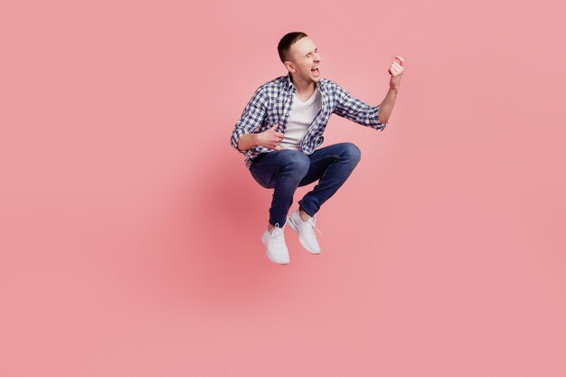 Foto de tamaño completo de chico joven feliz sonrisa positiva saltar tocar guitarra aislado sobre fondo de color rosa