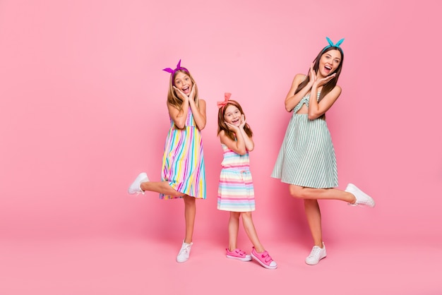 Foto de tamaño completo de hermanos alegres gritando wow omg tocando sus rostros con diadema de falda de vestido aislado sobre fondo rosa