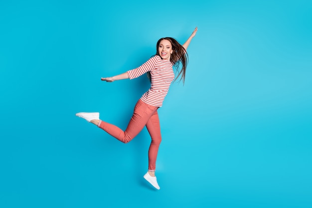 Foto de tamaño completo de niña descuidada saltar disfrutar de fin de semana tiempo libre viajes de otoño llevar ropa de buen humor aislado sobre fondo de color azul