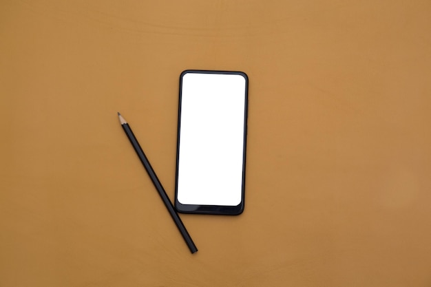Foto de teléfono inteligente con pantalla blanca y lápiz sobre fondo de cuero amarillo