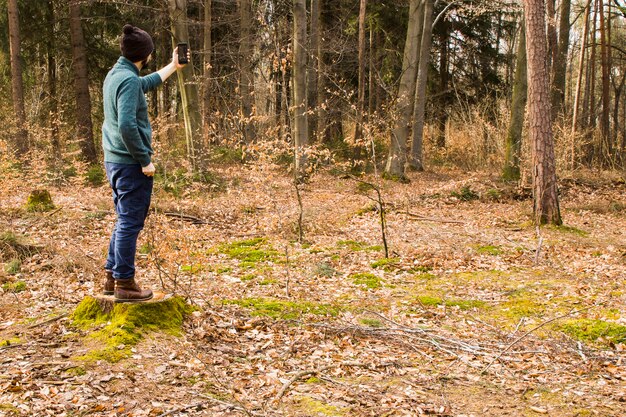 Foto de toma de hombre con teléfono inteligente en el bosque