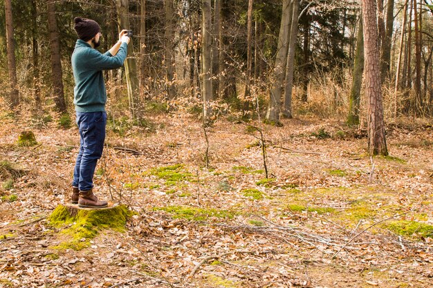 Foto de toma de hombre con teléfono inteligente en el bosque