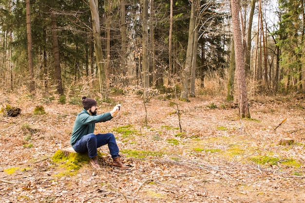 Foto de toma de hombre con teléfono inteligente en el bosque