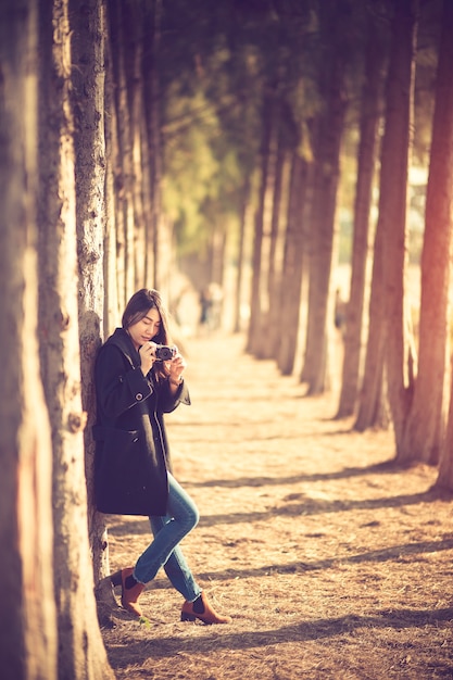 Foto de toma de mujer hipster feliz y con estilo con cámara de fotos en el fondo