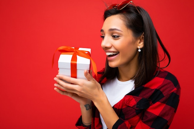 Foto tomada de bastante positivo sonriente joven morena mujer aislada sobre fondo rojo vistiendo de pared