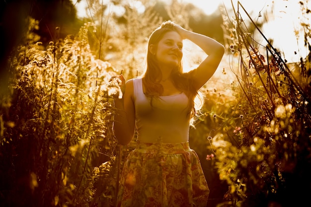 Foto de tonos de joven morena con cabello largo posando en el campo temprano en la mañana