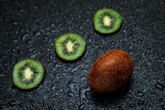 Foto foto tropical kiwi fresco meio cortado em fundo preto com gotas de água