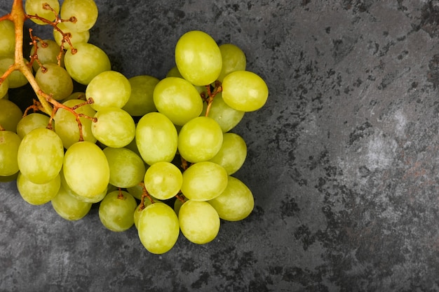 Foto de uva verde sobre un fondo oscuro de mármol. Uvas volumétricas. Un racimo de arbusto de uva verde.