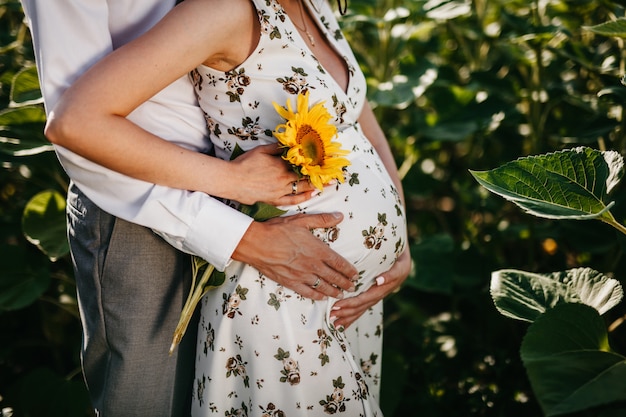 Foto de verano con una niña embarazada y un girasol