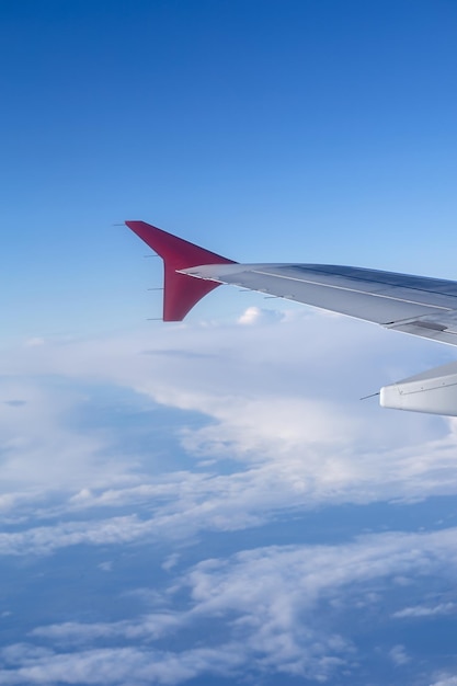 Foto vertical el ala de un avión volador contra el fondo de las nubes