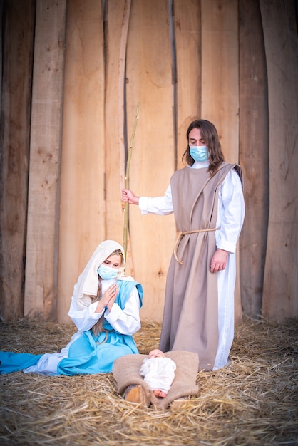 Foto vertical de un belén con los personajes con máscaras mientras adoraban al bebé Jesús