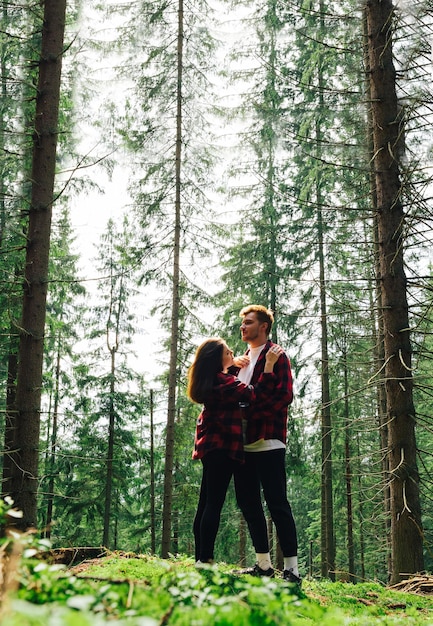 Foto vertical casal romântico homem e mulher enquanto caminhava em uma floresta de montanha em uma escalada